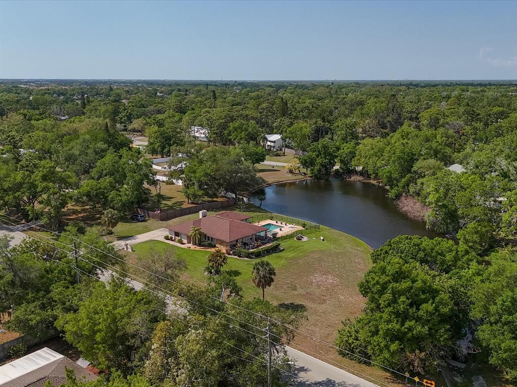 An aerial view shows a single-story house with a pool beside a small lake — 3927 DESOTO ROAD, SARASOTA, FL