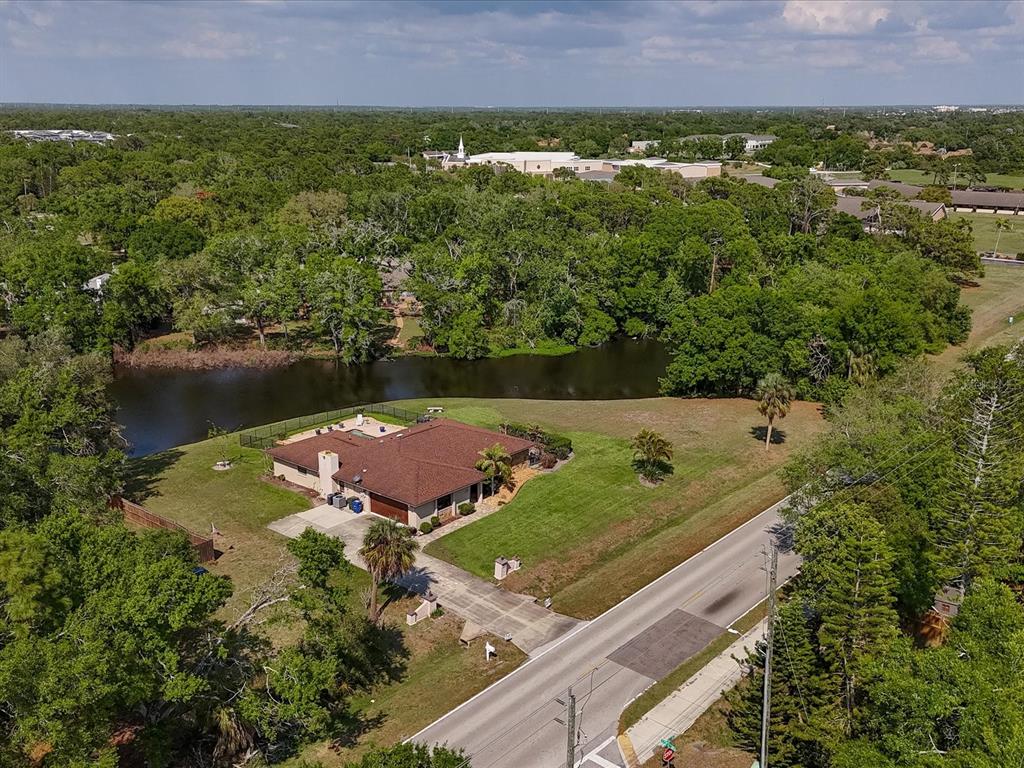 An aerial view shows a single-story house with a pool next to a pond — 3927 DESOTO ROAD, SARASOTA, FL