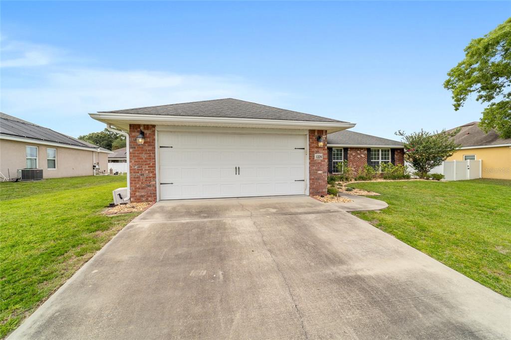 A single-story house with a brick-front garage, concrete driveway, and a light-colored roof — 1226 SE 65TH CIRCLE, OCALA, FL