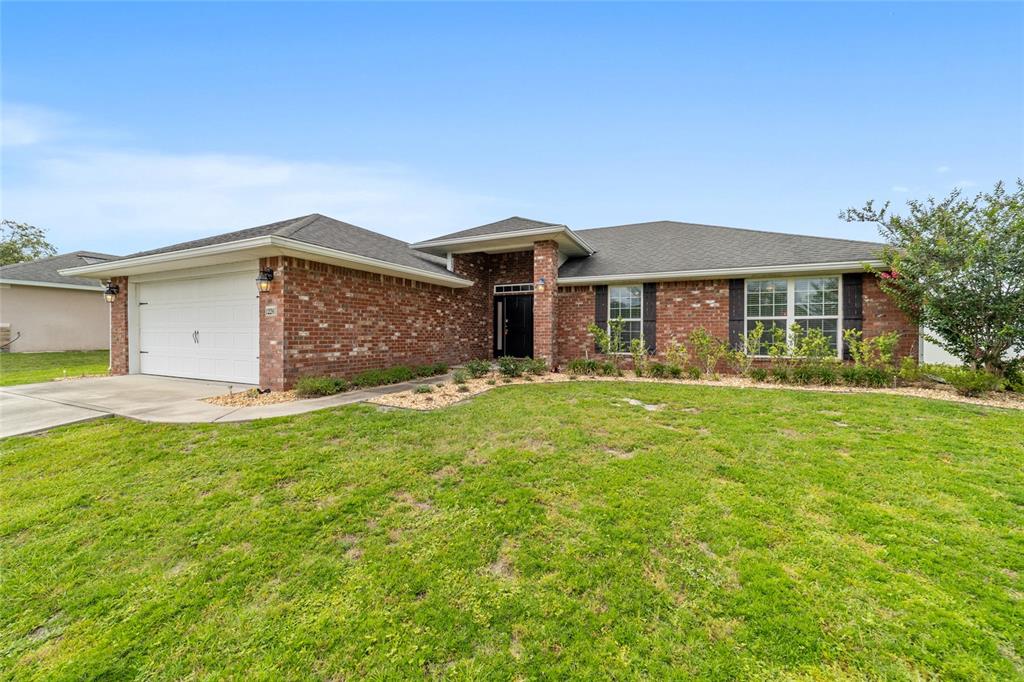 A single-story brick house with a two-car garage and a front lawn — 1226 SE 65TH CIRCLE, OCALA, FL