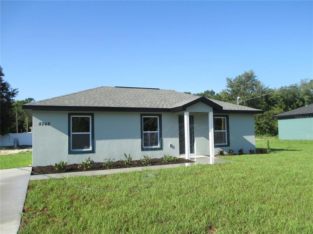 A single-story house with a gray stucco exterior, a hip roof, and a small porch — 5748 NW 5TH STREET, OCALA, FL