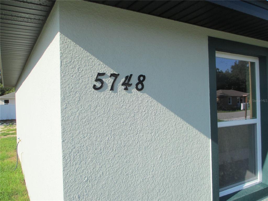 The exterior wall of a house displays the house number 5748 next to a window — 5748 NW 5TH STREET, OCALA, FL