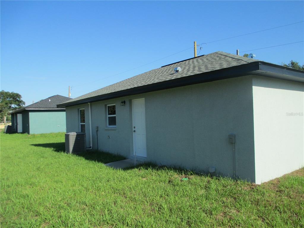 The exterior of a light-colored, single-story house with a gray shingled roof and grass yard — 5748 NW 5TH STREET, OCALA, FL