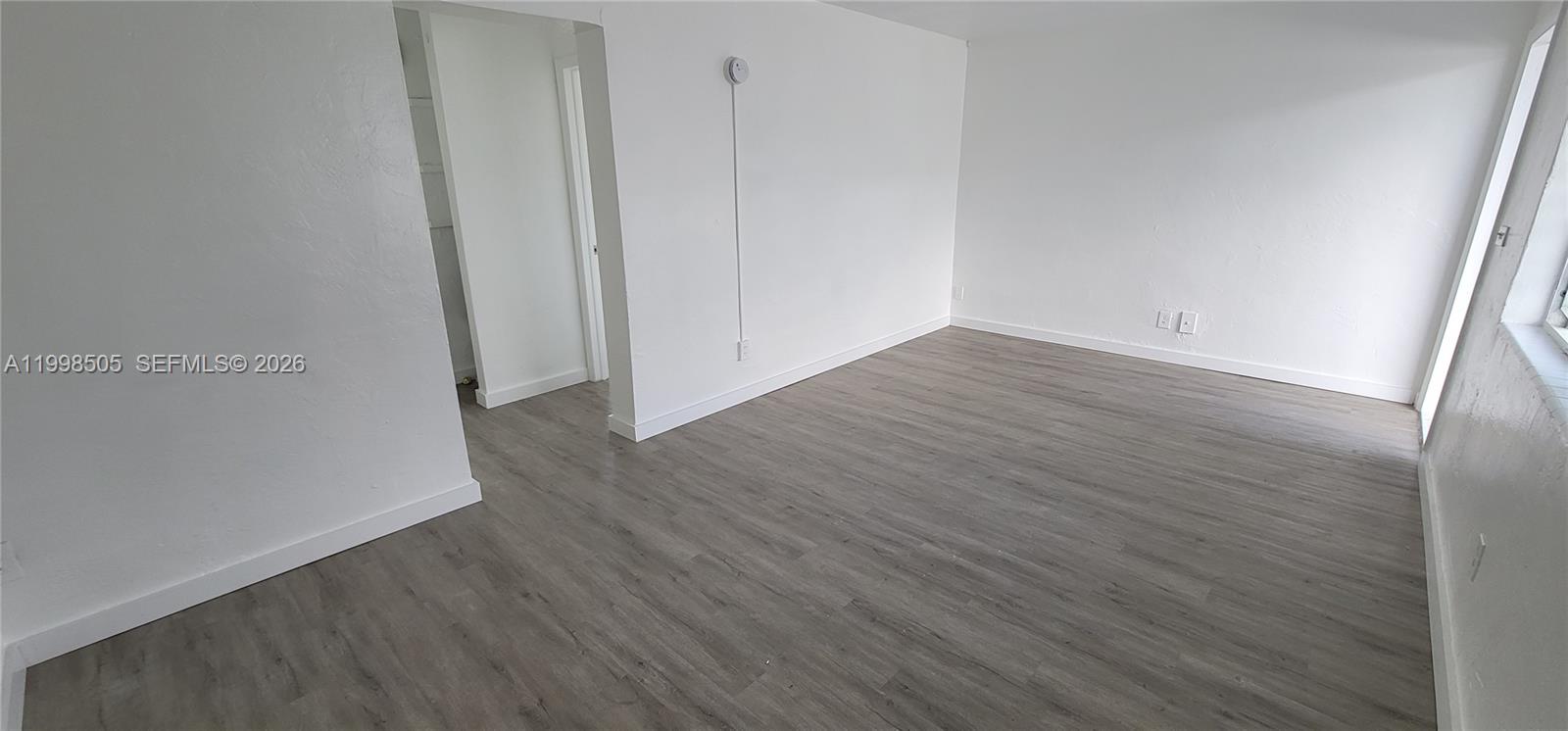 An empty room features white walls, gray wood-look flooring, and a doorway leading to a closet — 111 SW 18th Ave, Miami FL 33135, MIAMI, FL