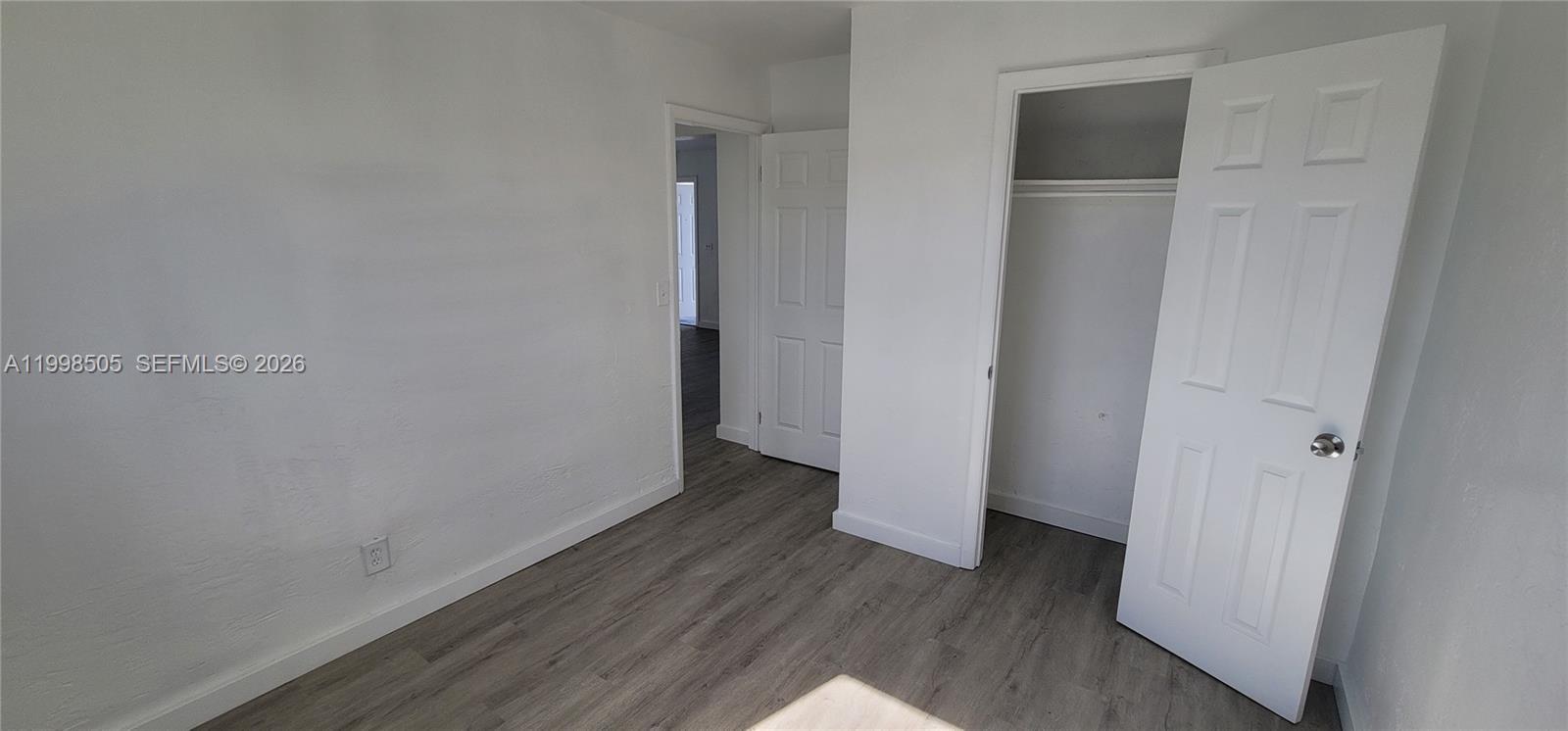 An empty room features white walls, gray wood-look flooring, and two open doorways — 111 SW 18th Ave, Miami FL 33135, MIAMI, FL