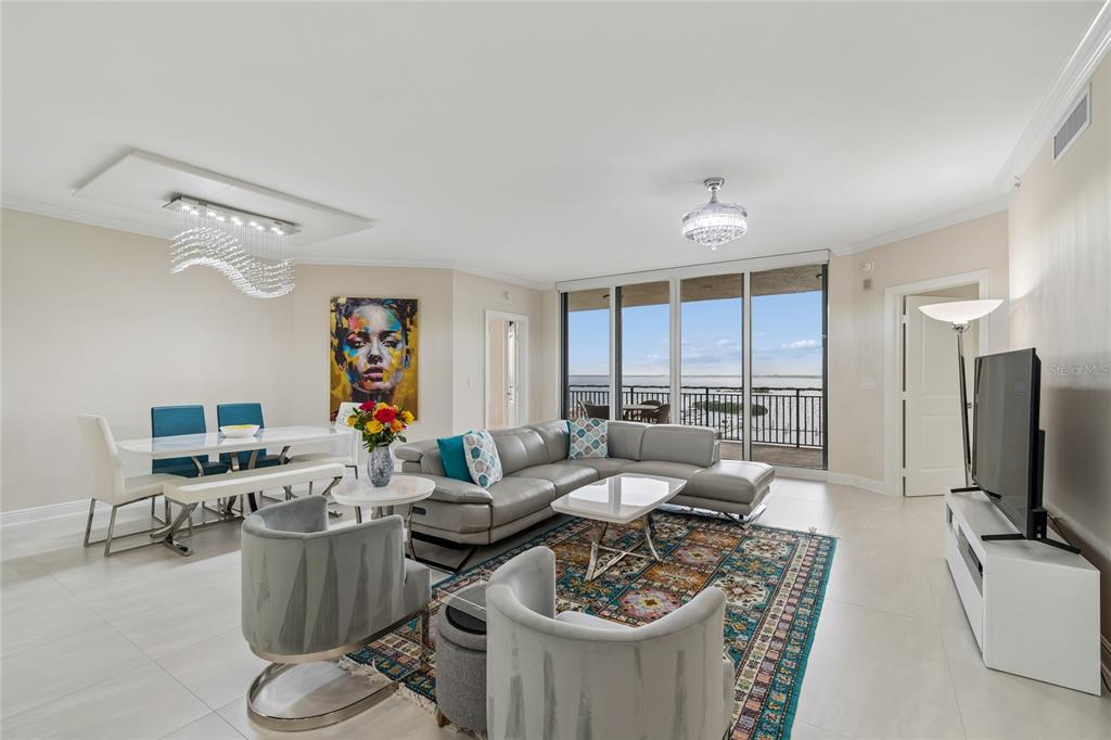 A modern living and dining area features a gray sectional, patterned rug, and balcony view — 5823 BOWEN DANIEL DRIVE UNIT 1103, TAMPA, FL
