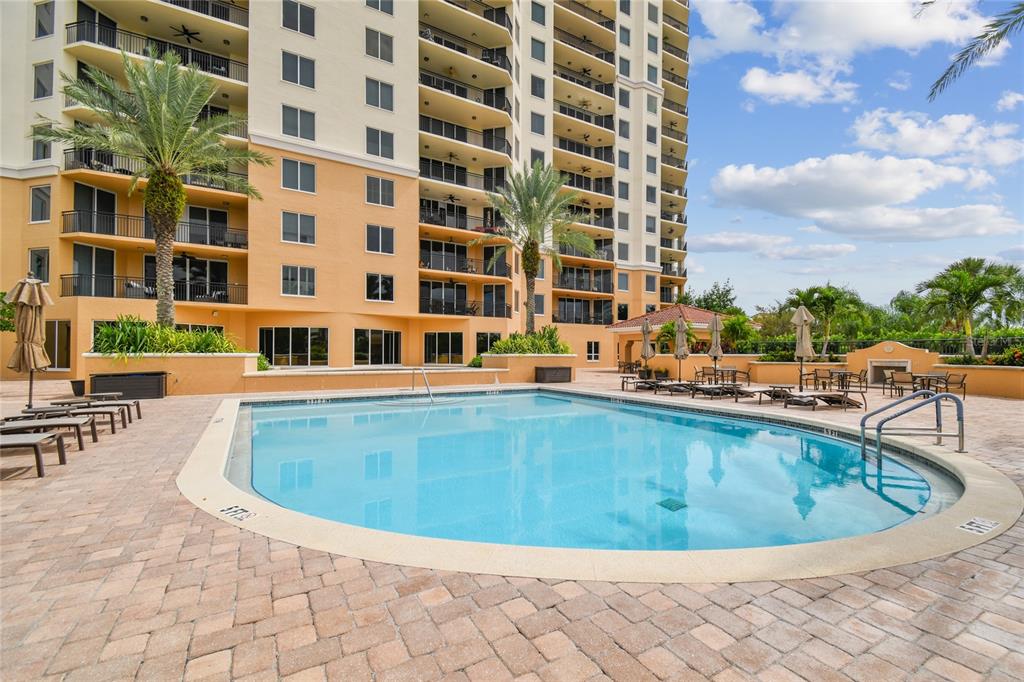 A swimming pool sits on a paved patio in front of a tall residential building — 5823 BOWEN DANIEL DRIVE UNIT 1103, TAMPA, FL
