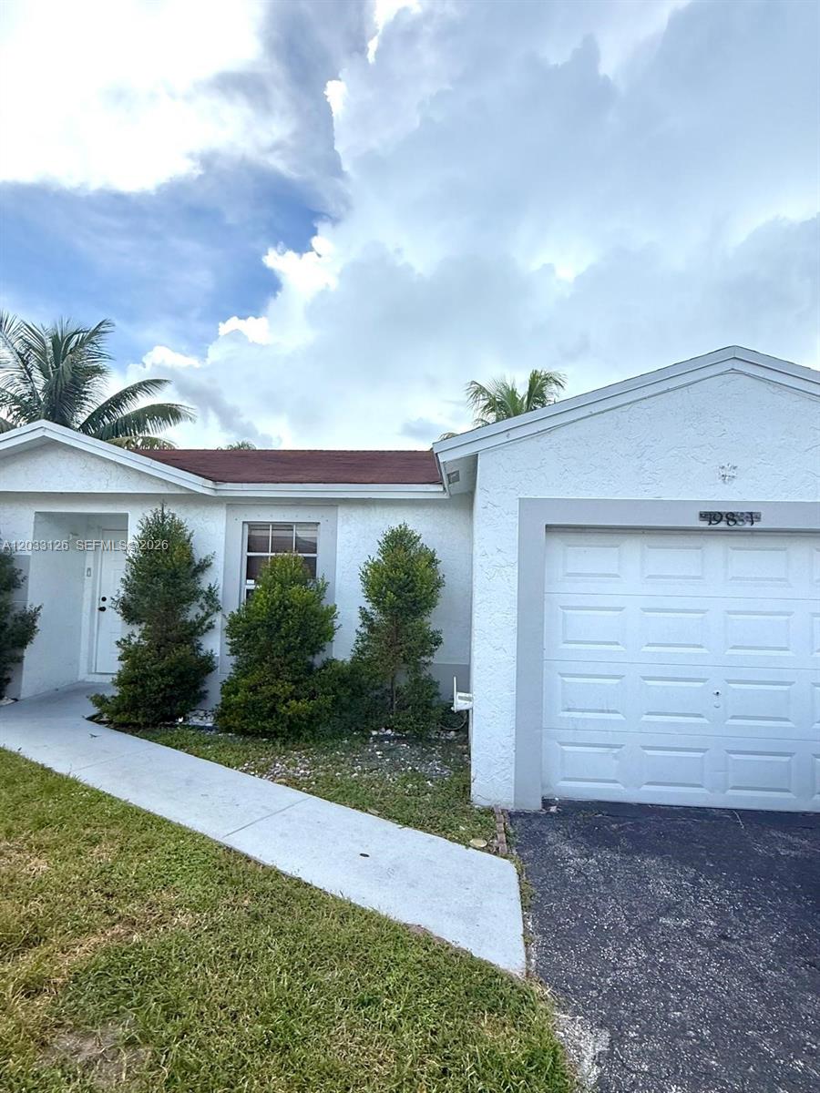 A single-story house features a white stucco exterior, a garage, and a front walkway — 19831 NW 65th Ct # 0, Hialeah FL 33015, HIALEAH, FL