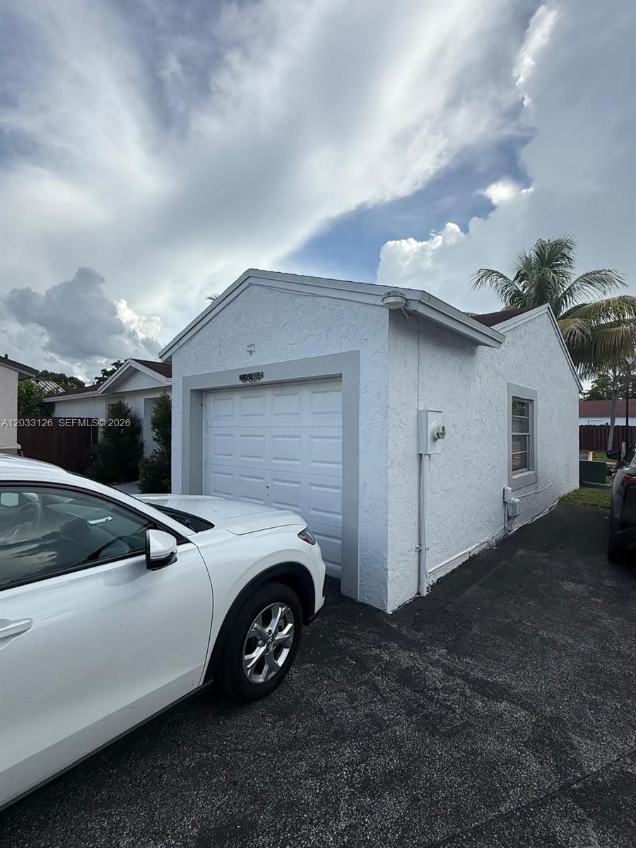 A white detached garage with a single door sits next to a paved driveway — 19831 NW 65th Ct # 0, Hialeah FL 33015, HIALEAH, FL