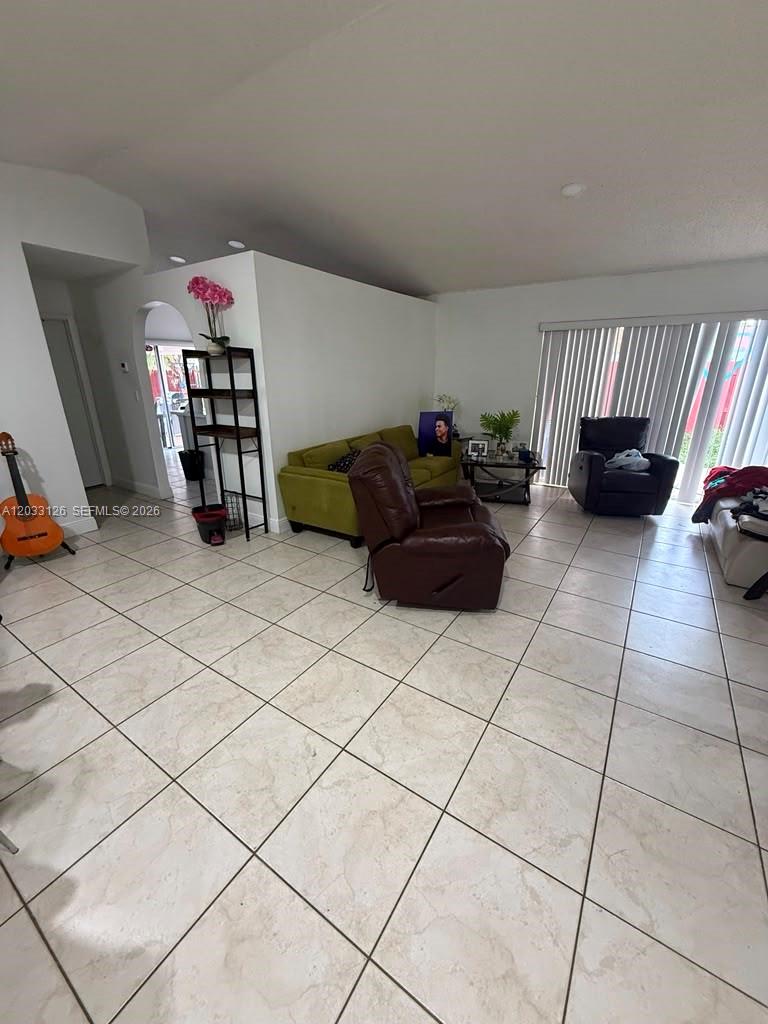 A living room features light tile flooring, a green sofa, and a brown recliner — 19831 NW 65th Ct # 0, Hialeah FL 33015, HIALEAH, FL