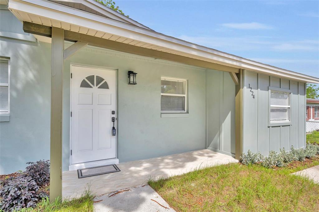 A light green house exterior features a white front door, a porch, and house numbers — 1224 HELEN STREET, APOPKA, FL