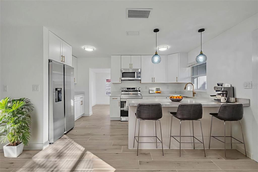 A bright kitchen features white cabinets, stainless steel appliances, and light-colored countertops — 1224 HELEN STREET, APOPKA, FL