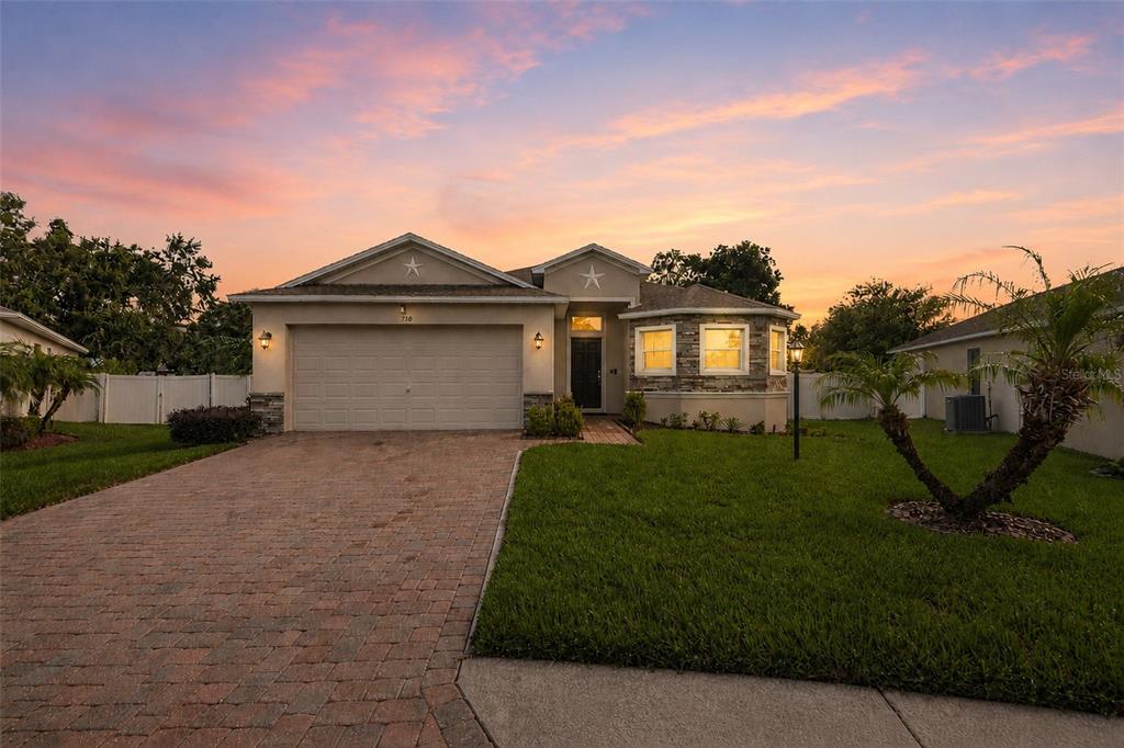 A single-story suburban house with a paved driveway, two-car garage, and a front lawn — 110 PROMENADE COURT, AUBURNDALE, FL