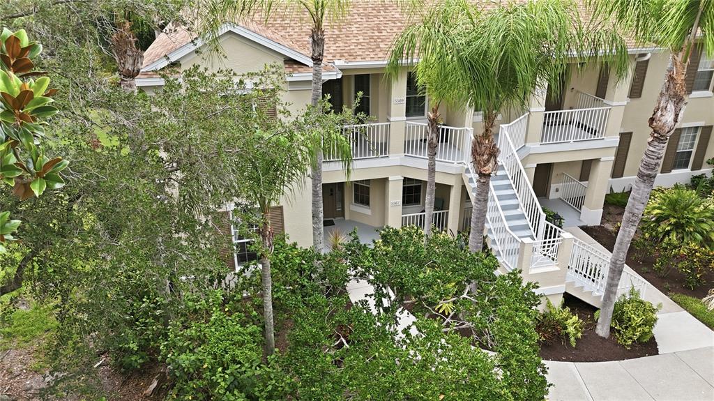 An exterior view of a two-story apartment building with white railings and palm trees — 5507 KEY WEST PLACE UNIT 5507, BRADENTON, FL