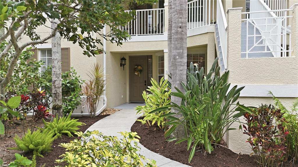 A concrete walkway leads to the front entrance of a two-story tan stucco building — 5507 KEY WEST PLACE UNIT 5507, BRADENTON, FL