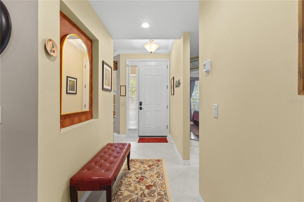 A foyer features a red leather bench, a patterned rug, and a white front door — 5507 KEY WEST PLACE UNIT 5507, BRADENTON, FL