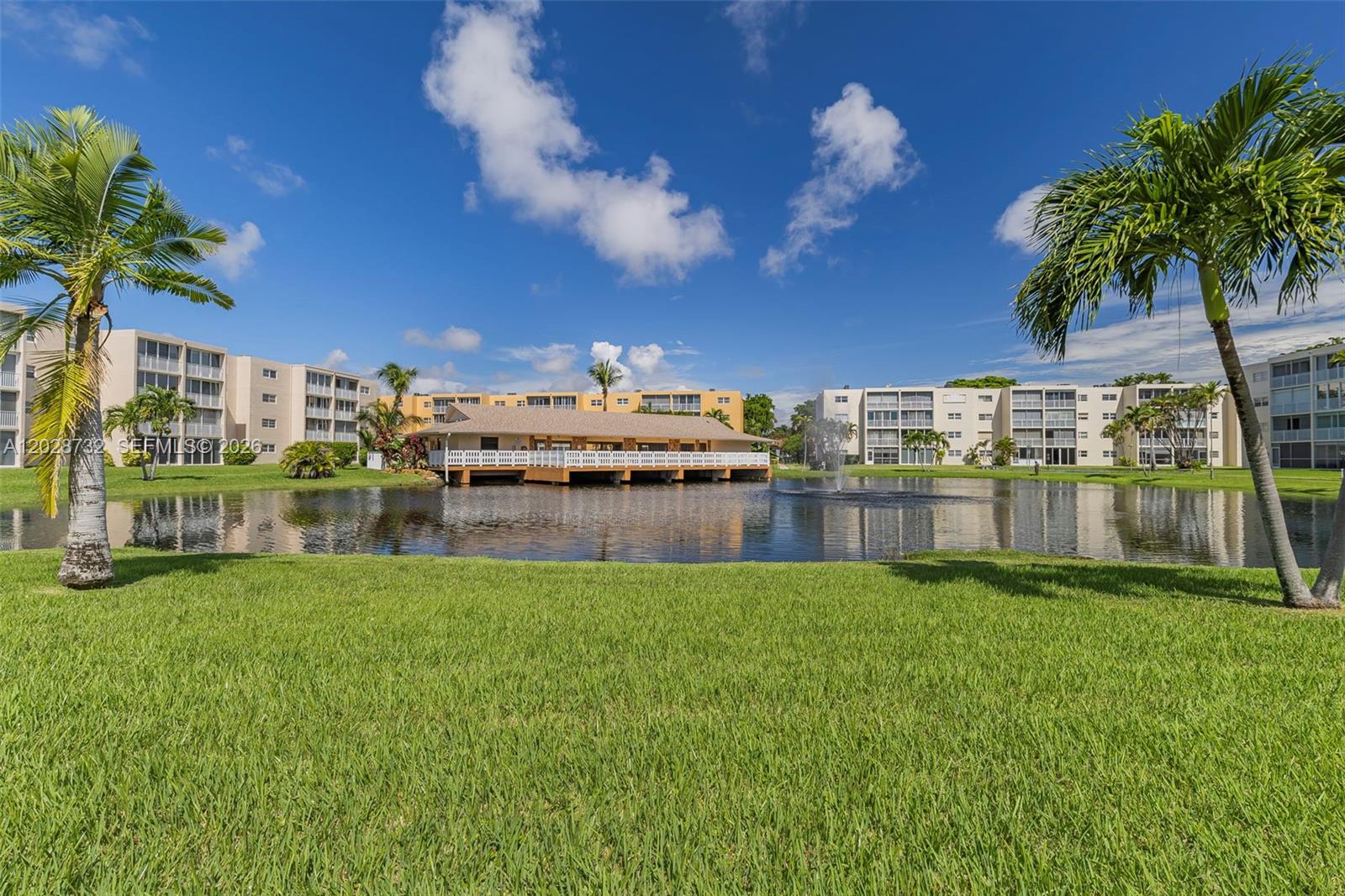 A pond with a fountain sits in front of a clubhouse surrounded by apartment buildings — 201 SE 11th Ter # 102, Dania Beach FL 33004, DANIA BEACH, FL