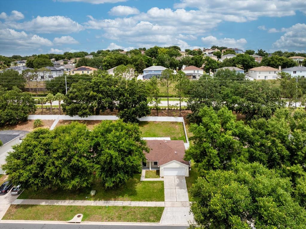 An aerial view shows a single-story house with a white garage and a fenced backyard — 1882 VALE DRIVE, CLERMONT, FL