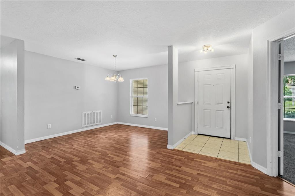 An entryway with tiled flooring leads into a dining area featuring wood-look flooring and walls — 1882 VALE DRIVE, CLERMONT, FL