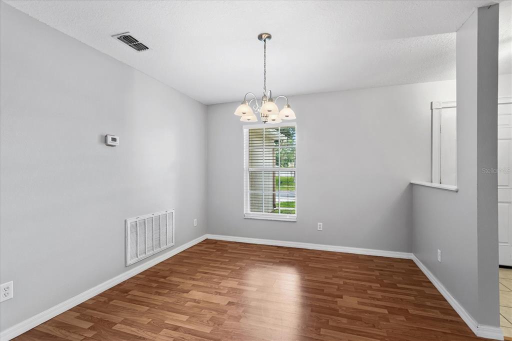 A dining room with light gray walls, wood-look flooring, a chandelier, and a window — 1882 VALE DRIVE, CLERMONT, FL
