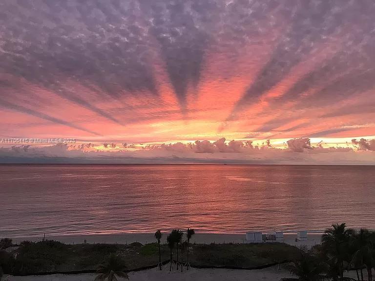 A view of a beach and ocean at sunset with a dramatic, colorful sky — 5601 Collins Ave # 9, Miami Beach FL 33140, MIAMI BEACH, FL