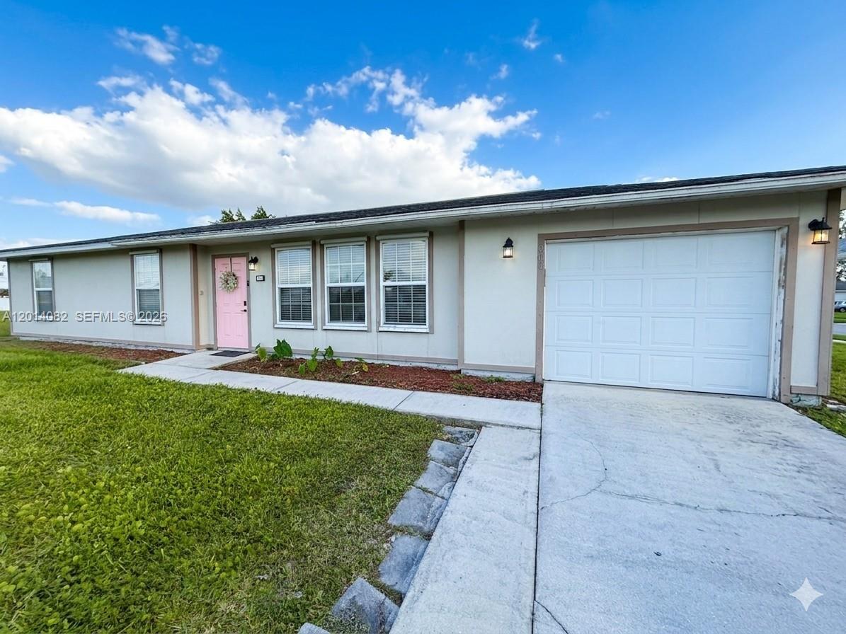 A single-story house features a light-colored exterior, a pink front door, and a white garage — 900 NE 18th TER, Cape Coral FL 33909, CAPE CORAL, FL