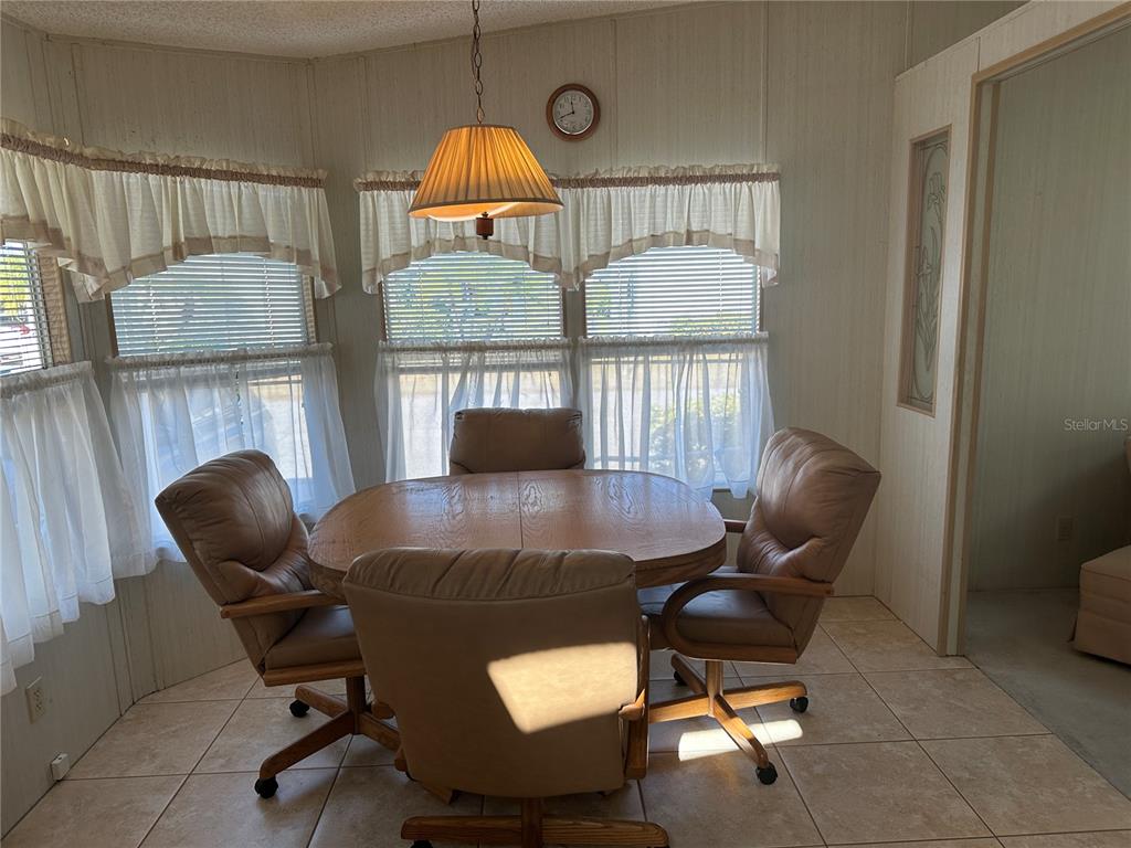 A dining area features a round wooden table, four rolling chairs, and large bay windows — 449 LANDSEDGE DRIVE, NORTH PORT, FL