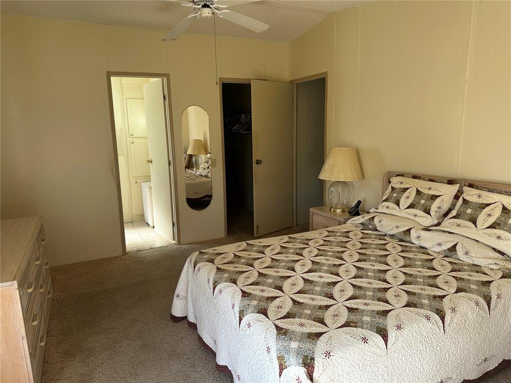 A bedroom features a bed with a patterned quilt, carpeted flooring, and two open doorways — 449 LANDSEDGE DRIVE, NORTH PORT, FL