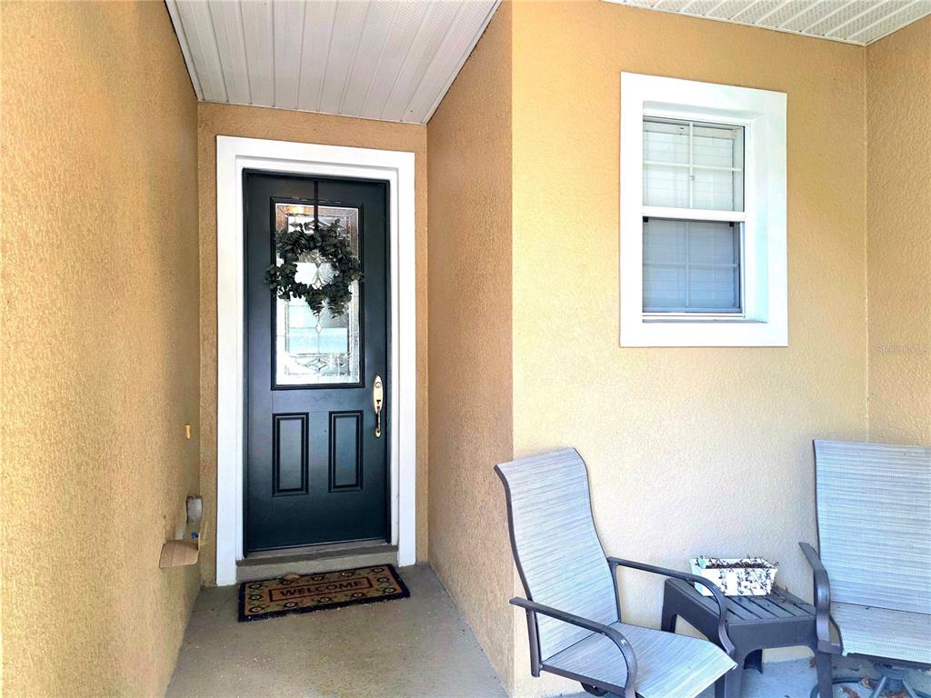 A covered front porch features a black door with a wreath and two patio chairs — 430 PENNY ROYAL PLACE, OVIEDO, FL