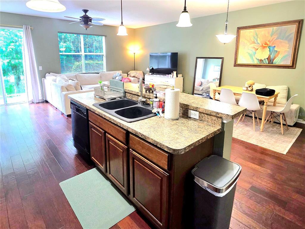 A kitchen island with a double sink sits in an open-concept living and dining area — 430 PENNY ROYAL PLACE, OVIEDO, FL