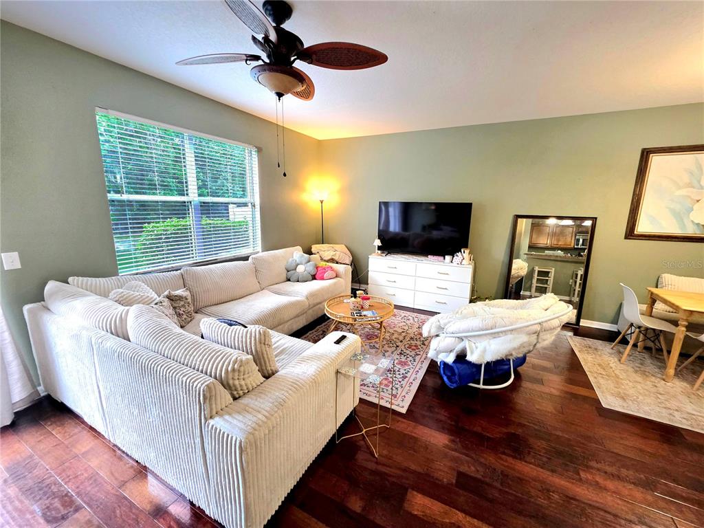 A living room features a large sectional sofa, a television on a dresser, and hardwood floors — 430 PENNY ROYAL PLACE, OVIEDO, FL