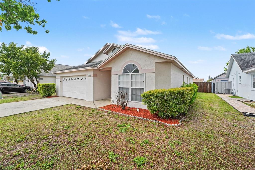 A single-story house with a white stucco exterior, a two-car garage, and a front lawn — 204 KINGSHILL COURT SE, WINTER HAVEN, FL