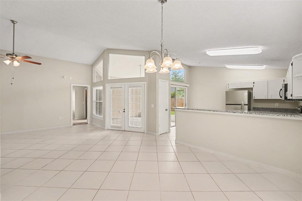 An open-concept living and dining area with tile floors, a chandelier, and a kitchen counter — 204 KINGSHILL COURT SE, WINTER HAVEN, FL