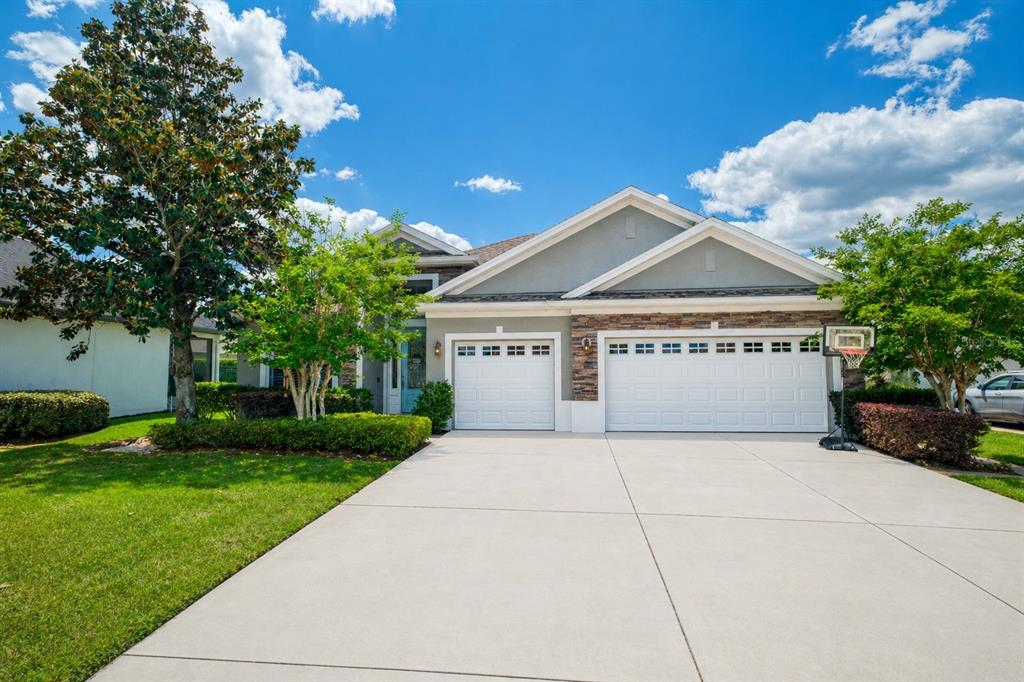 A single-story suburban house with a three-car garage, stone accents, and a concrete driveway — 863 OAKBRANCH PLACE, SANFORD, FL