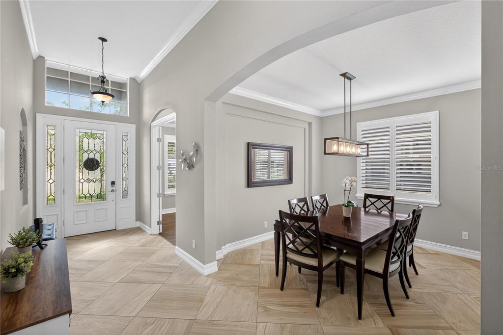 A dining room with tile floors, a wooden table, and a chandelier near an entryway — 863 OAKBRANCH PLACE, SANFORD, FL