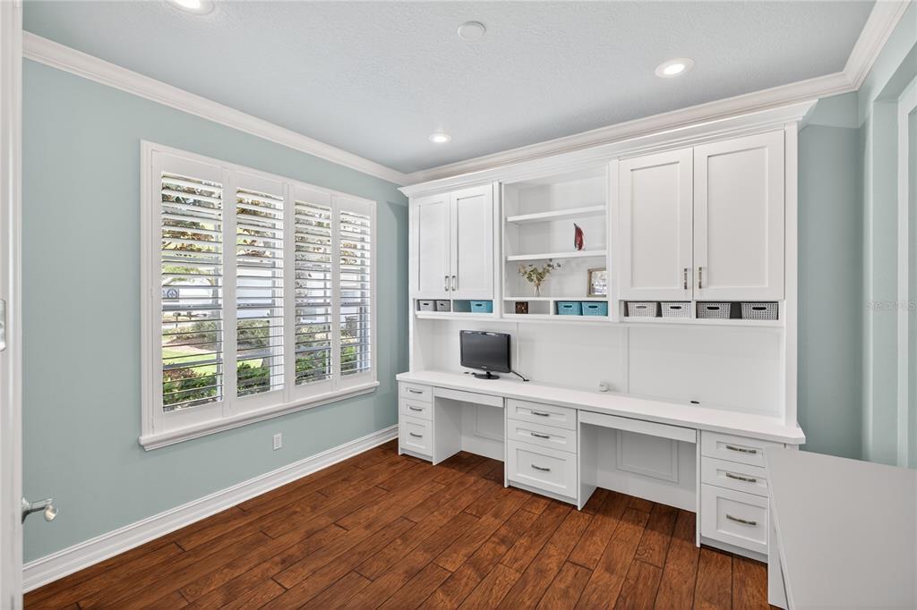 A home office with light blue walls, hardwood floors, and a built-in white desk unit — 863 OAKBRANCH PLACE, SANFORD, FL