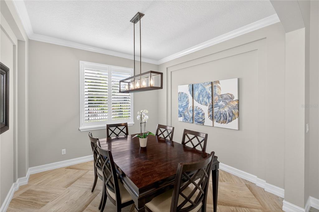 A dining room features a dark wood table, lattice-back chairs, a linear chandelier, and tile flooring — 863 OAKBRANCH PLACE, SANFORD, FL