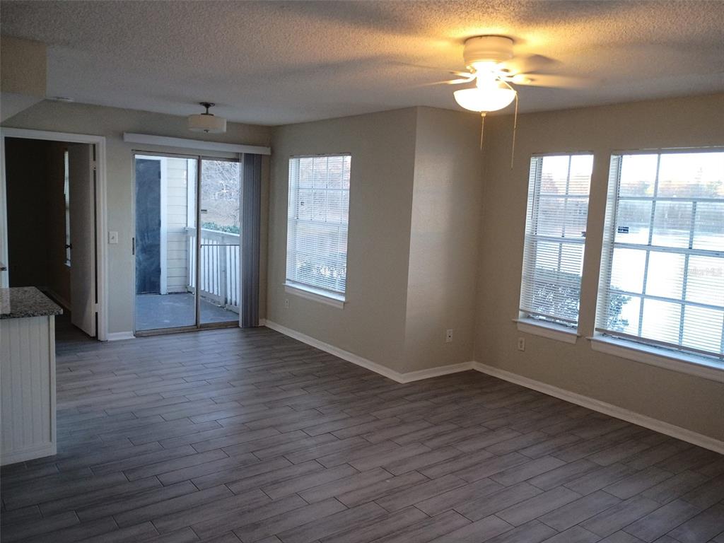 An empty living room features gray wood-look tile flooring, a ceiling fan, and sliding doors — 1037 S HIAWASSEE ROAD UNIT 2818, ORLANDO, FL