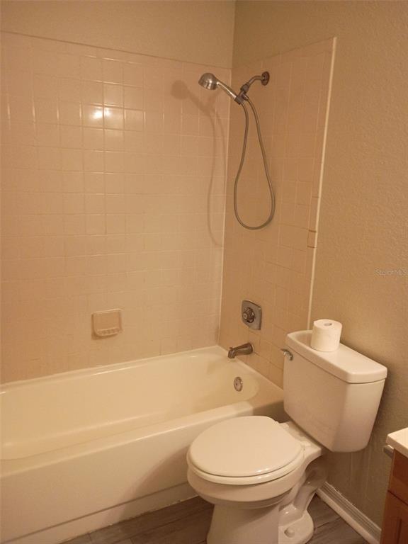 A bathroom features a white bathtub with a showerhead and a white toilet — 1037 S HIAWASSEE ROAD UNIT 2818, ORLANDO, FL