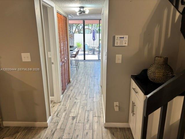A hallway with wood-look tile flooring leads to a glass door opening onto a patio — 10621 SW 79th Ter, Miami FL 33173, MIAMI, FL