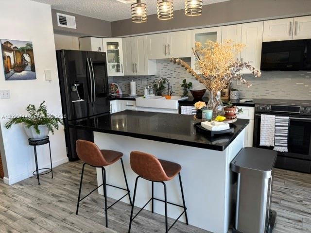 A modern kitchen features white cabinets, black countertops, a central island, and stainless steel appliances — 10621 SW 79th Ter, Miami FL 33173, MIAMI, FL