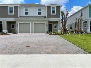 A two-story townhouse exterior features a paved driveway, two garage doors, and light-colored siding — 1309 AXEL GRAESON AVENUE, KISSIMMEE, FL