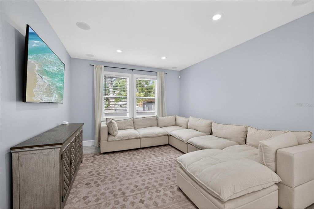 A living room features a large beige sectional sofa, a wooden media console, and a television — 4102 S TRASK STREET, TAMPA, FL