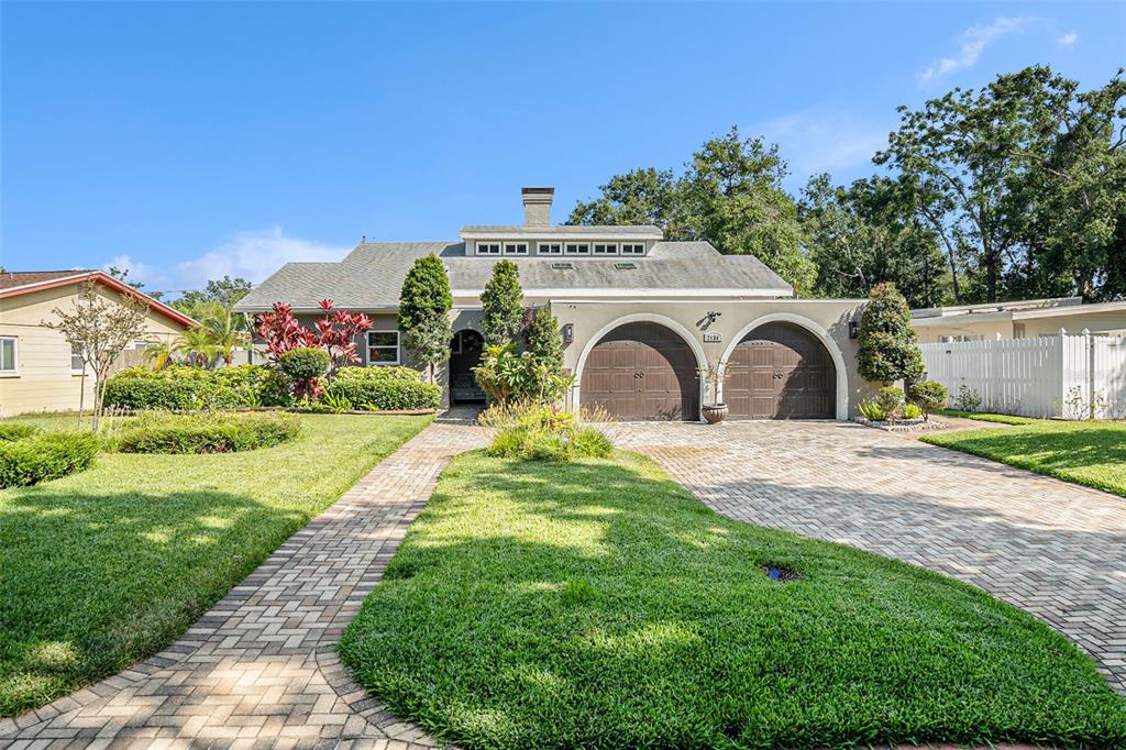A single-story house features a brick paver driveway, arched garage doors, and a central chimney — 2134 SERPENTINE CIRCLE S, ST PETERSBURG, FL