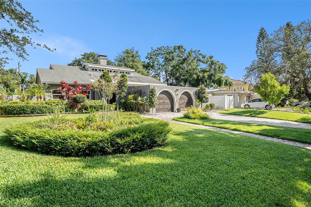 A single-story house with a gray exterior, arched garage doors, and a landscaped front yard — 2134 SERPENTINE CIRCLE S, ST PETERSBURG, FL