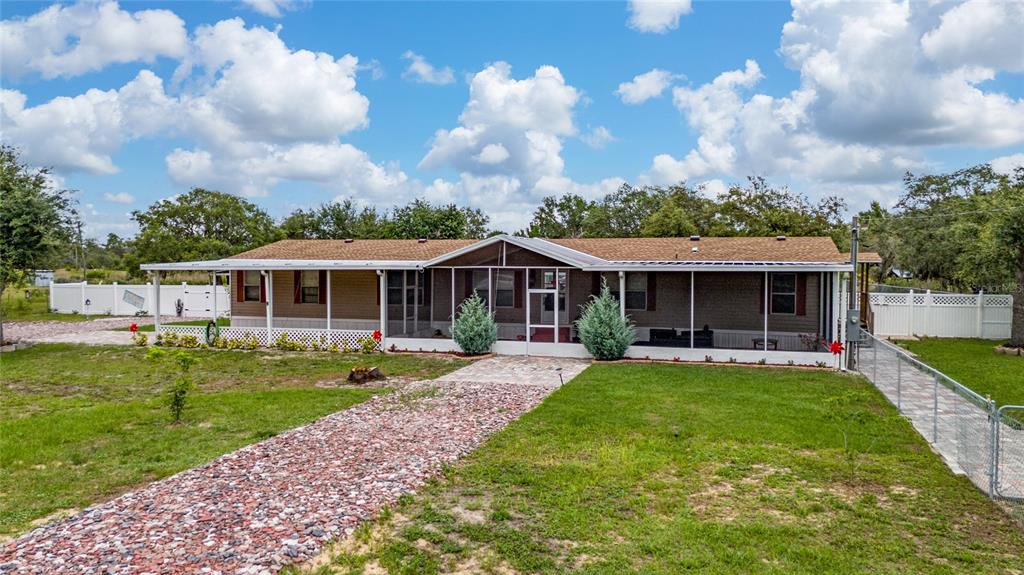 A single-story manufactured home features a large screened-in front porch and a gravel walkway — 4350 TIMMERMAN AVENUE, LAKE WALES, FL