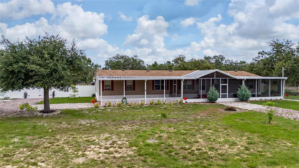 A single-story manufactured home with a full-length screened porch sits on a grassy lot — 4350 TIMMERMAN AVENUE, LAKE WALES, FL