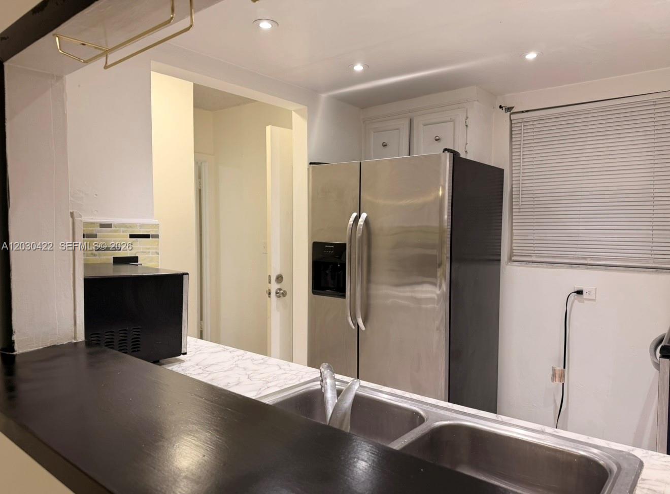 A kitchen features a stainless steel refrigerator, a double-basin sink, and a dark countertop — 1035 W 77th St # 211, Hialeah FL 33014, HIALEAH, FL