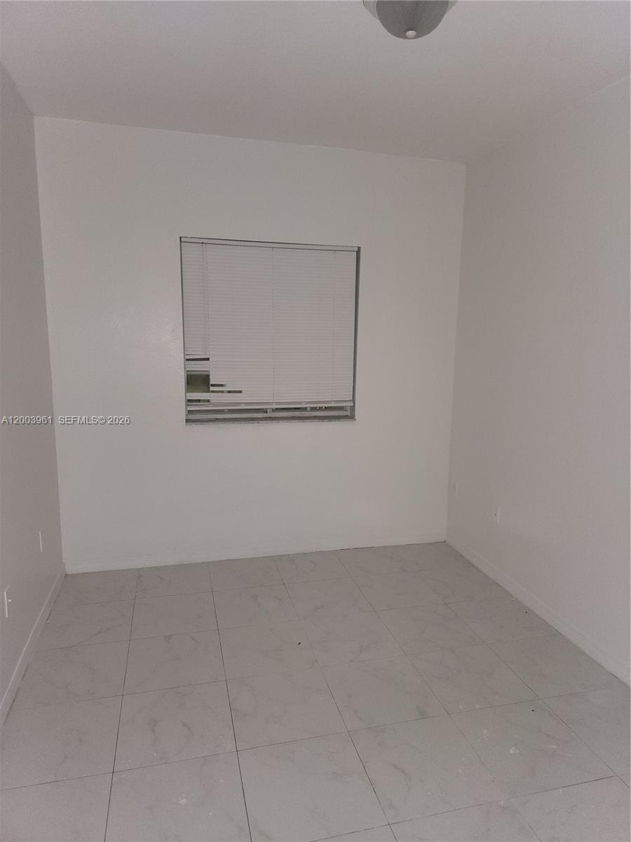A small, empty room features white walls, light-colored tile flooring, and a window with blinds — 6972 NW 179th St # 4, Hialeah FL 33015, HIALEAH, FL