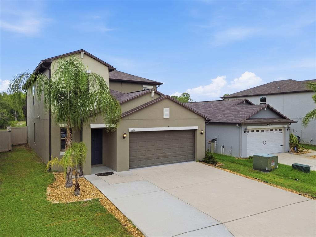 An aerial view of a two-story suburban house with a garage and a palm tree — 13393 MARBLE SANDS COURT E, HUDSON, FL
